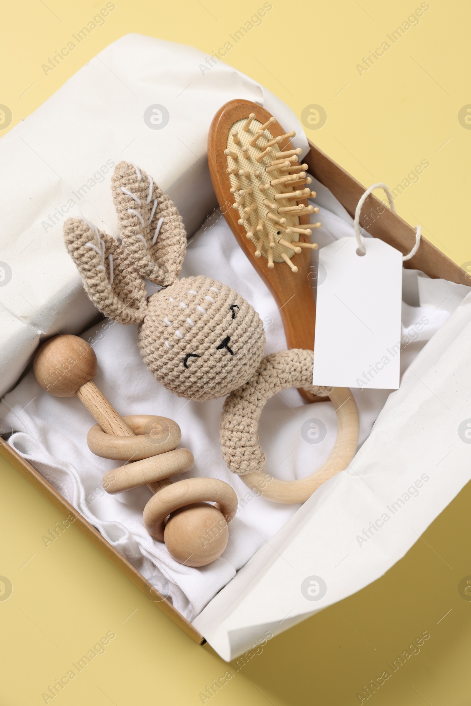 Photo of Different baby accessories and blank card in box on yellow background, top view