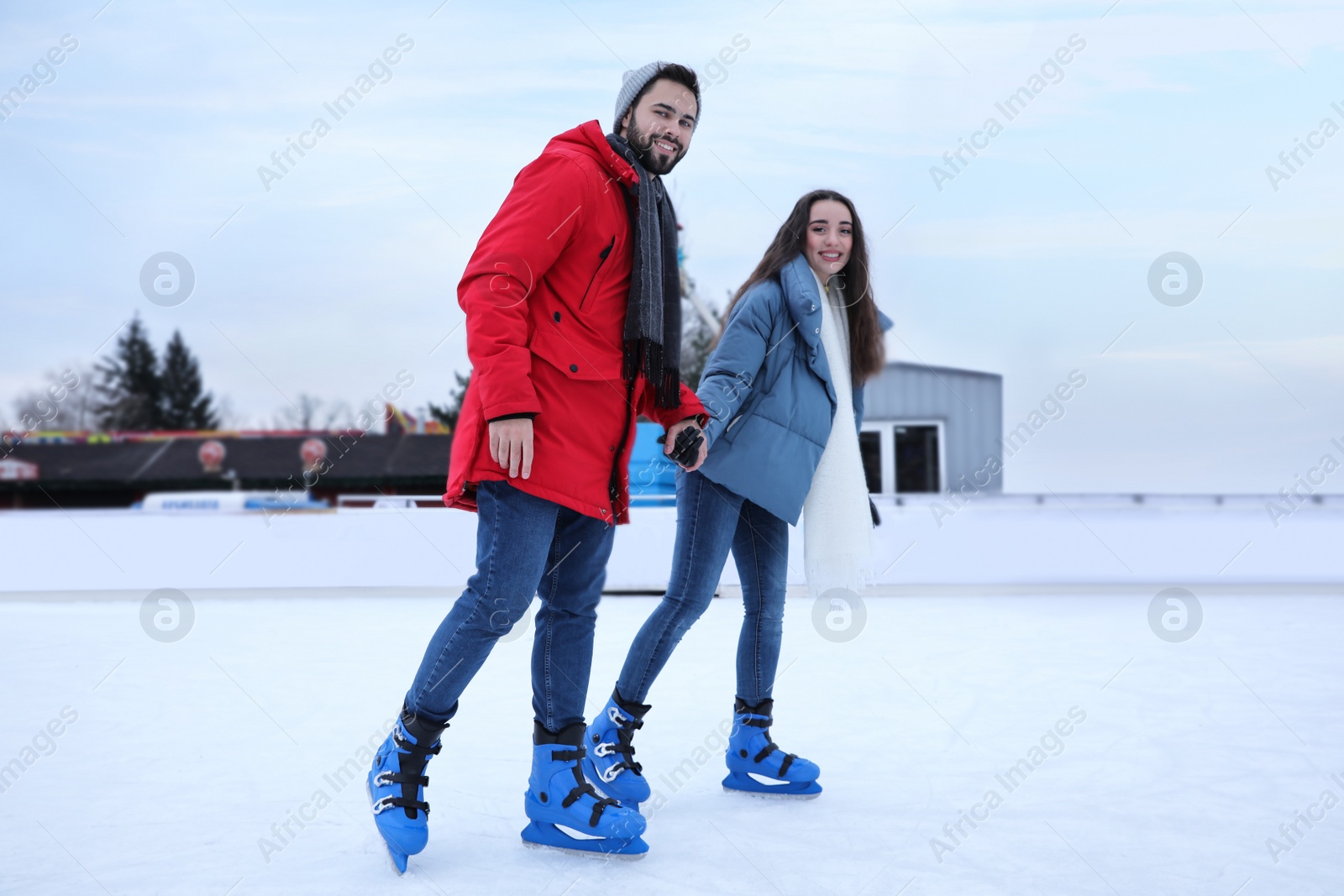 Image of Happy couple skating along ice rink outdoors