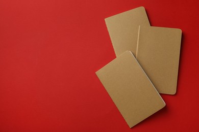 Photo of New stylish kraft planners on red background, top view. Space for text