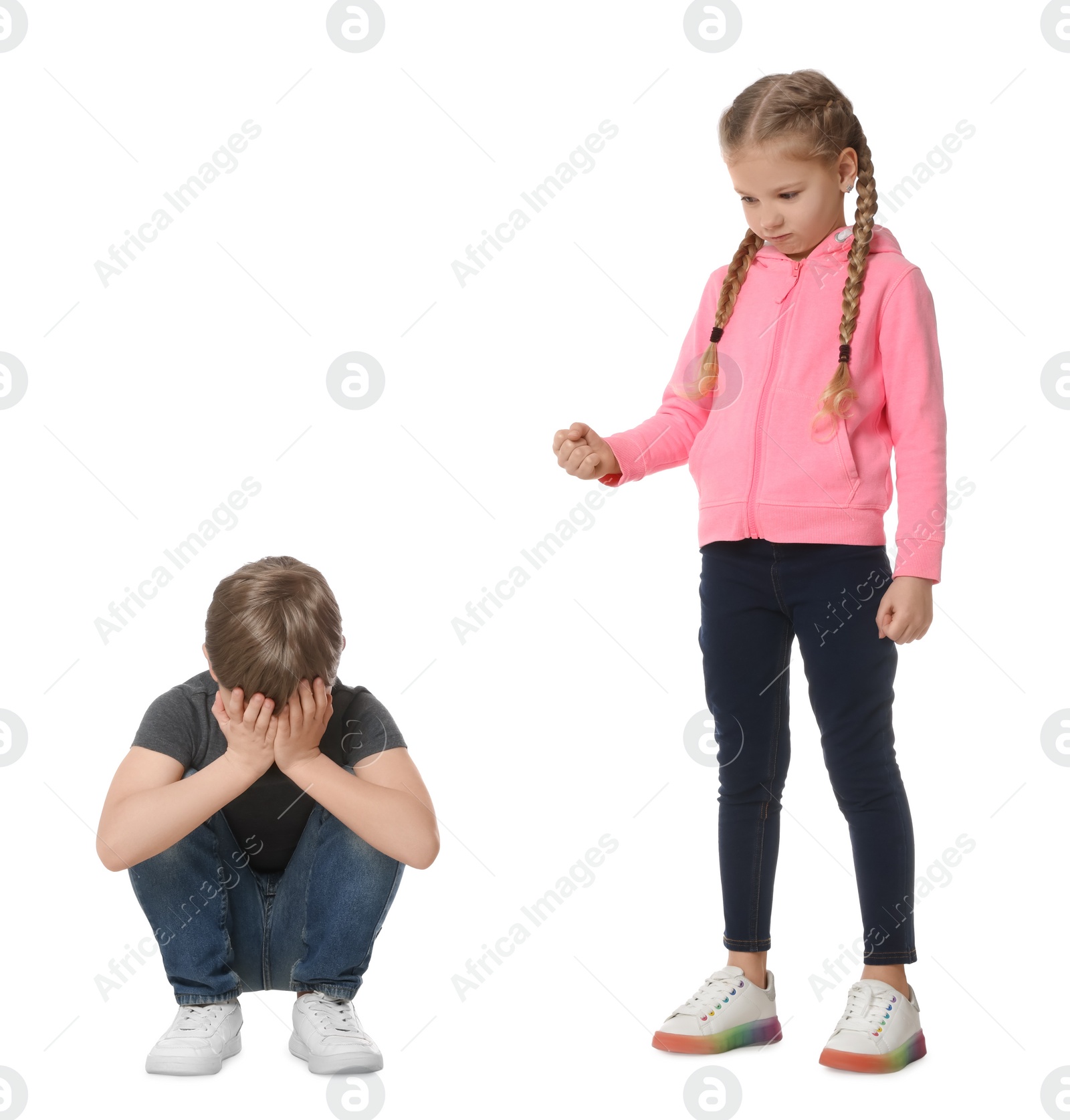 Photo of Girl with clenched fist looking at scared boy on white background. Children's bullying