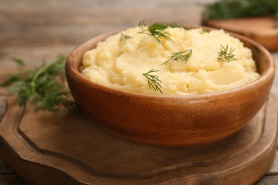 Photo of Bowl with mashed potatoes on wooden board