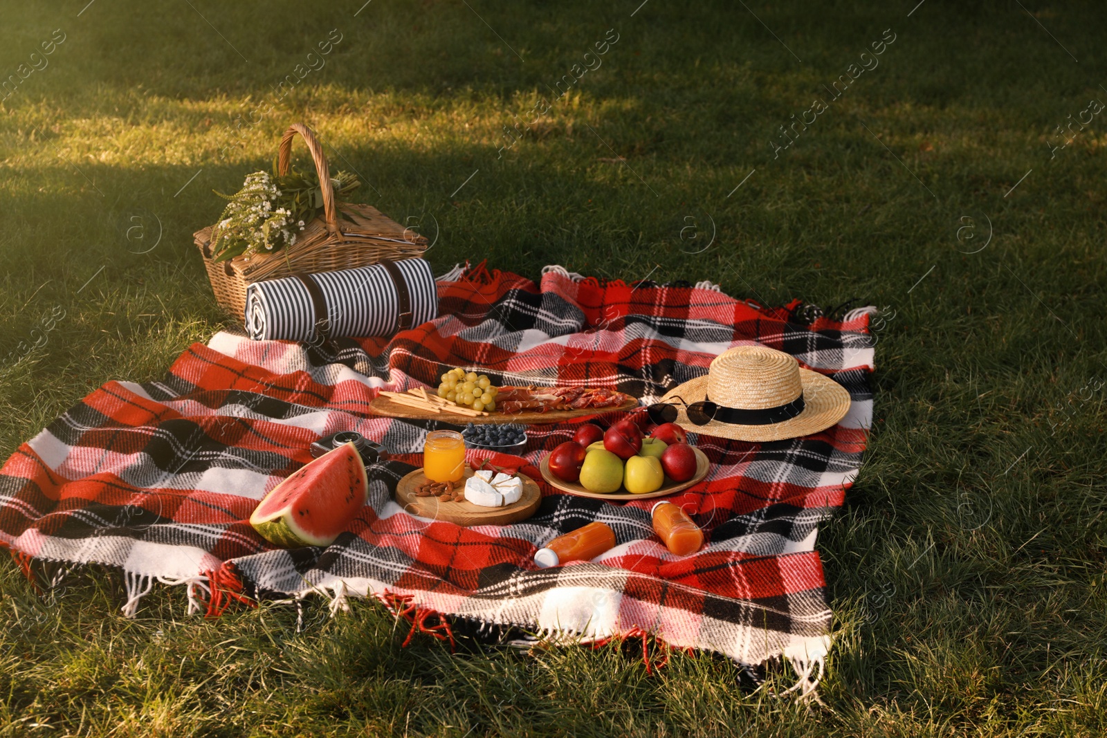 Photo of Picnic basket, food and drinks on plaid outdoors