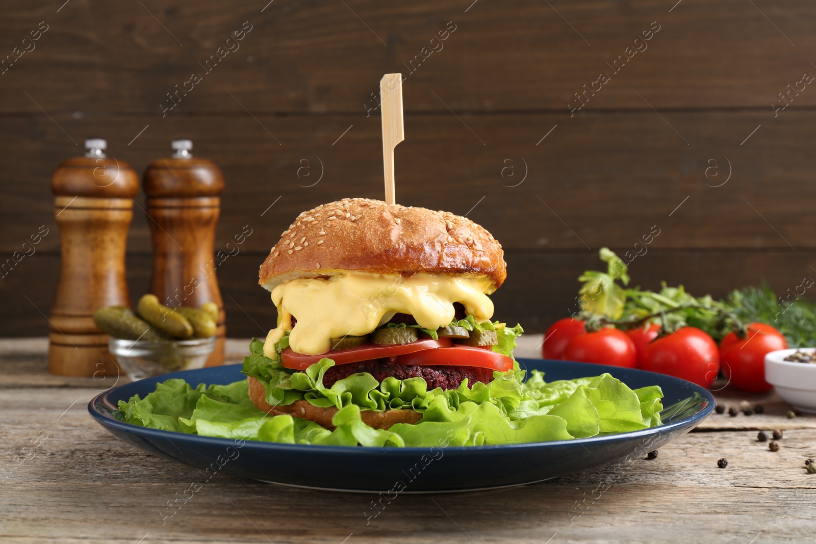 Photo of Delicious vegetarian burger and ingredients on wooden table