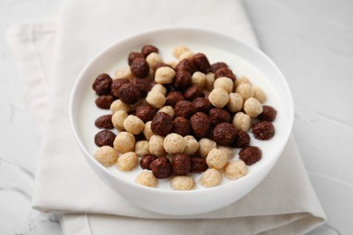 Photo of Breakfast cereal. Tasty corn balls with milk in bowl on white textured table, closeup