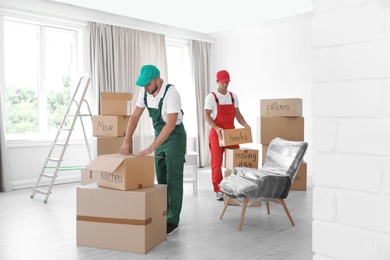 Male movers with boxes in new house