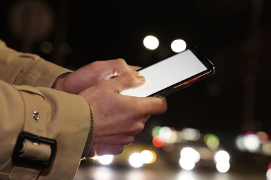 Photo of Man using smartphone on night city street, closeup