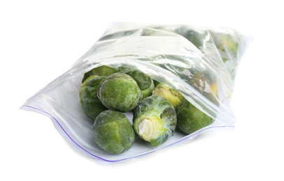 Photo of Frozen Brussels sprouts in plastic bag isolated on white. Vegetable preservation