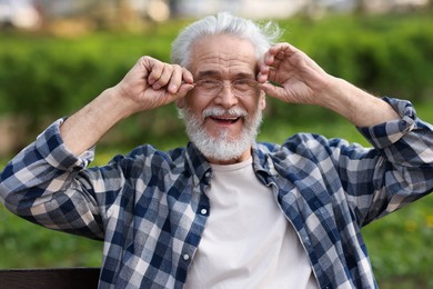 Photo of Portrait of happy grandpa with glasses on bench in park