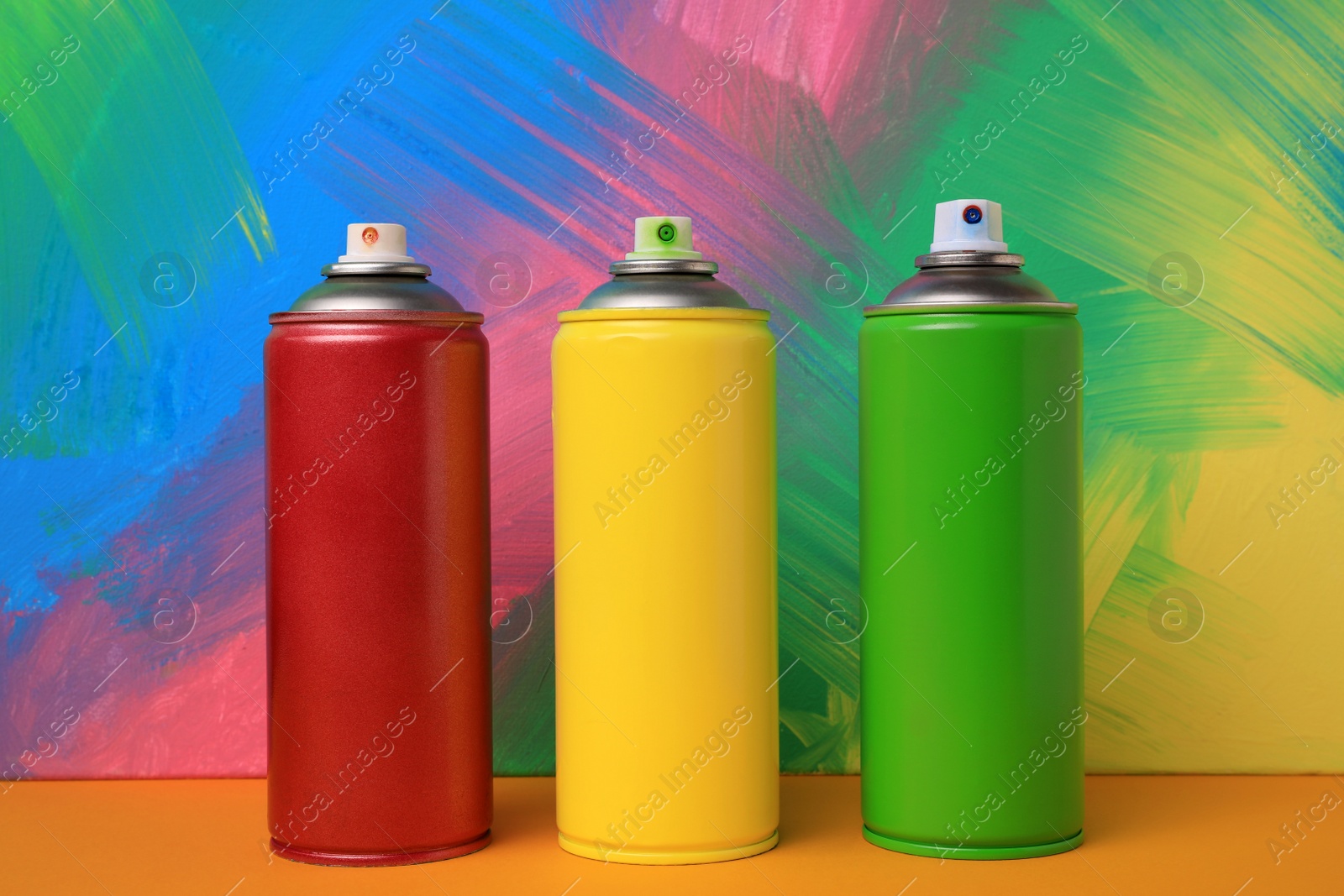 Photo of Cans of different spray paints on color background. Graffiti supplies