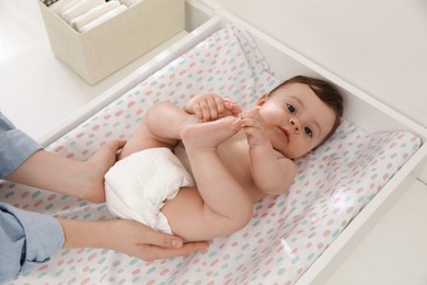 Photo of Mother changing baby's diaper on table at home, closeup