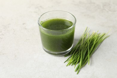 Photo of Wheat grass drink in glass and fresh sprouts on light table