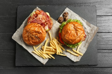Photo of Burgers with bacon and french fries on table, top view