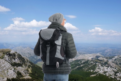 Image of Tourist with travel backpack enjoying mountain landscape during vacation trip