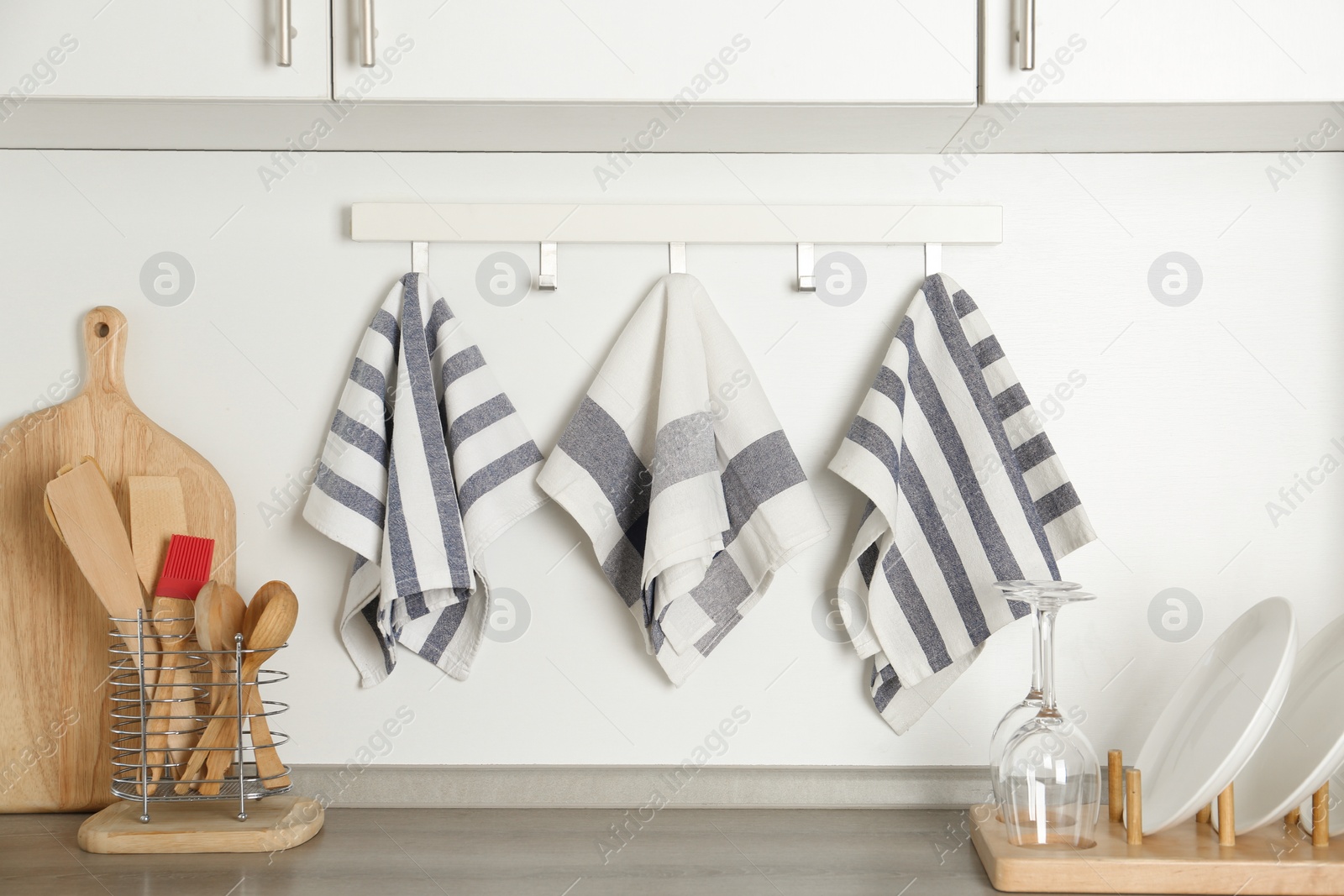 Photo of Different kitchen towels hanging on hook rack indoors