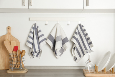 Photo of Different kitchen towels hanging on hook rack indoors