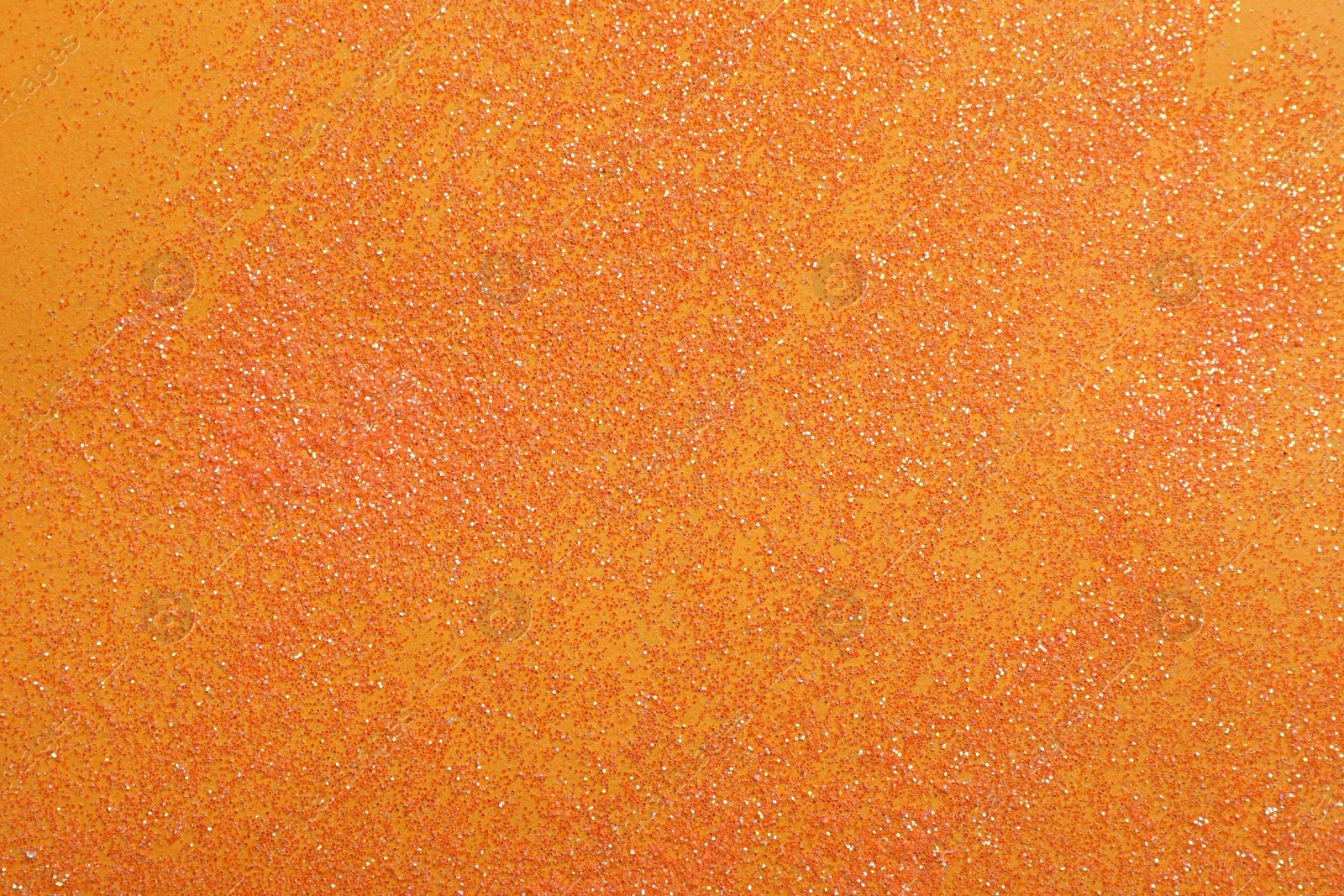 Photo of Shiny bright glitter on orange background, flat lay