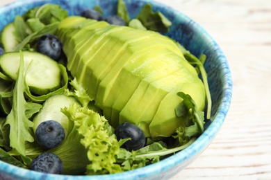 Photo of Delicious avocado salad with blueberries in bowl on table, closeup