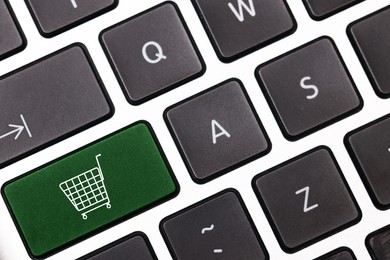 Image of Internet store. Green button with shopping cart on computer keyboard, top view