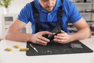 Male technician repairing hard drive at table indoors, closeup