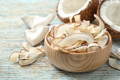 Photo of Tasty coconut chips on light blue wooden table