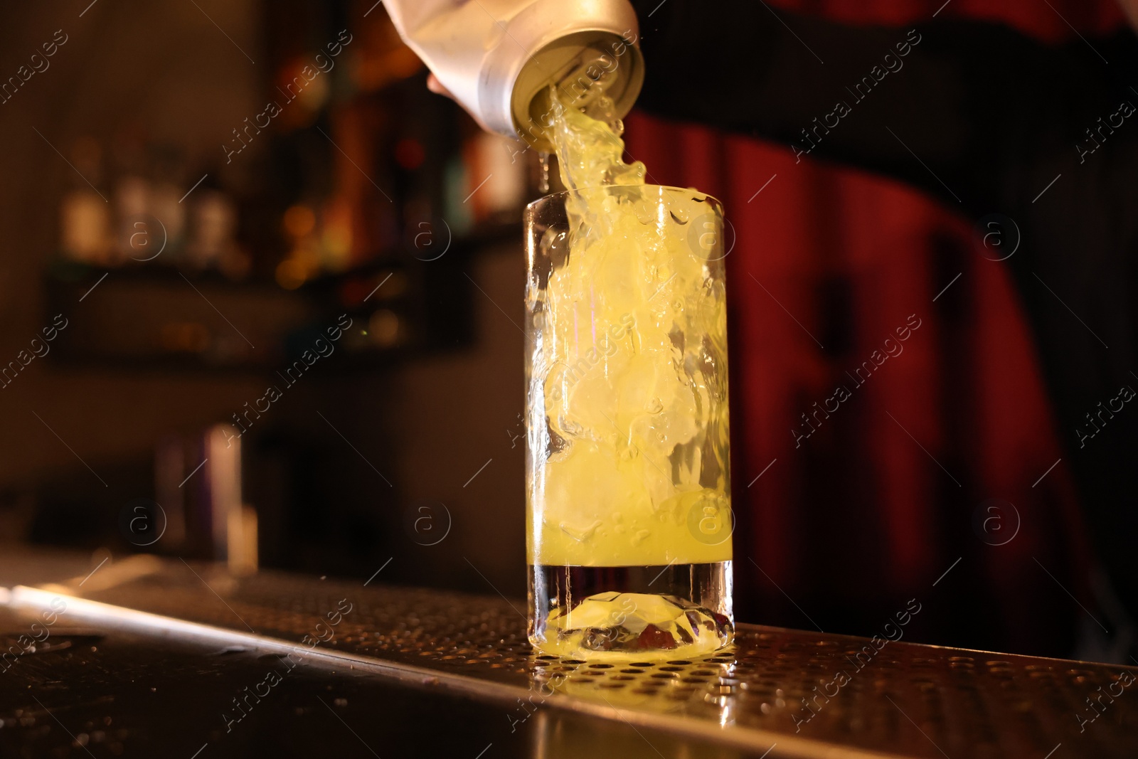 Photo of Bartender pouring energy drink into glass at counter in bar, selective focus