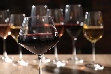 Tasty red wine in glass against blurred background, space for text