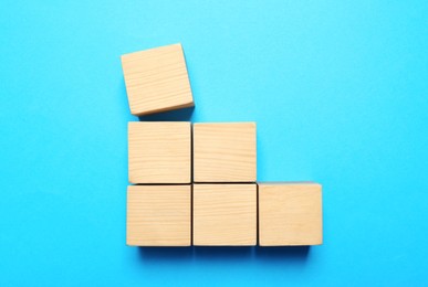 Photo of Blank cubes on light blue background, flat lay with space for text. Idea concept