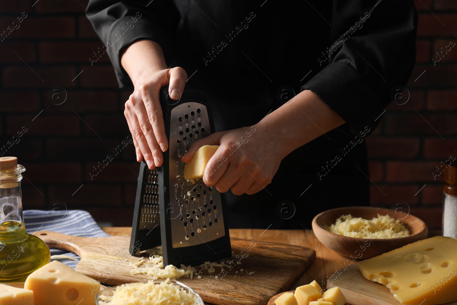 Photo of Woman grating cheese at wooden table, closeup