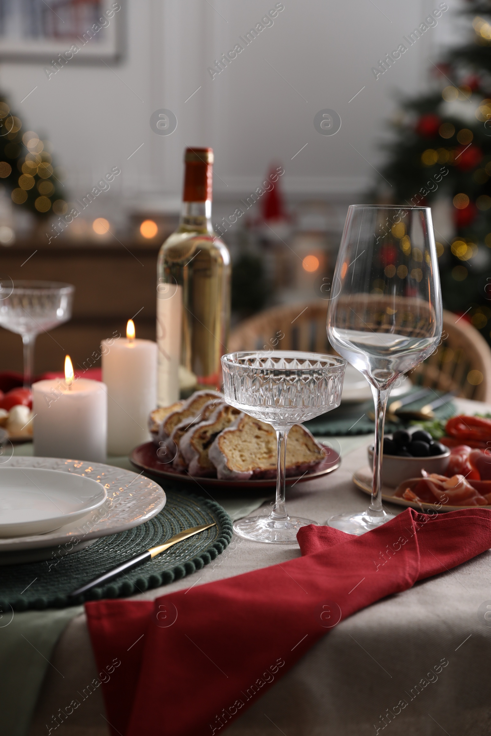 Photo of Christmas table setting with burning candles, appetizers and dishware indoors