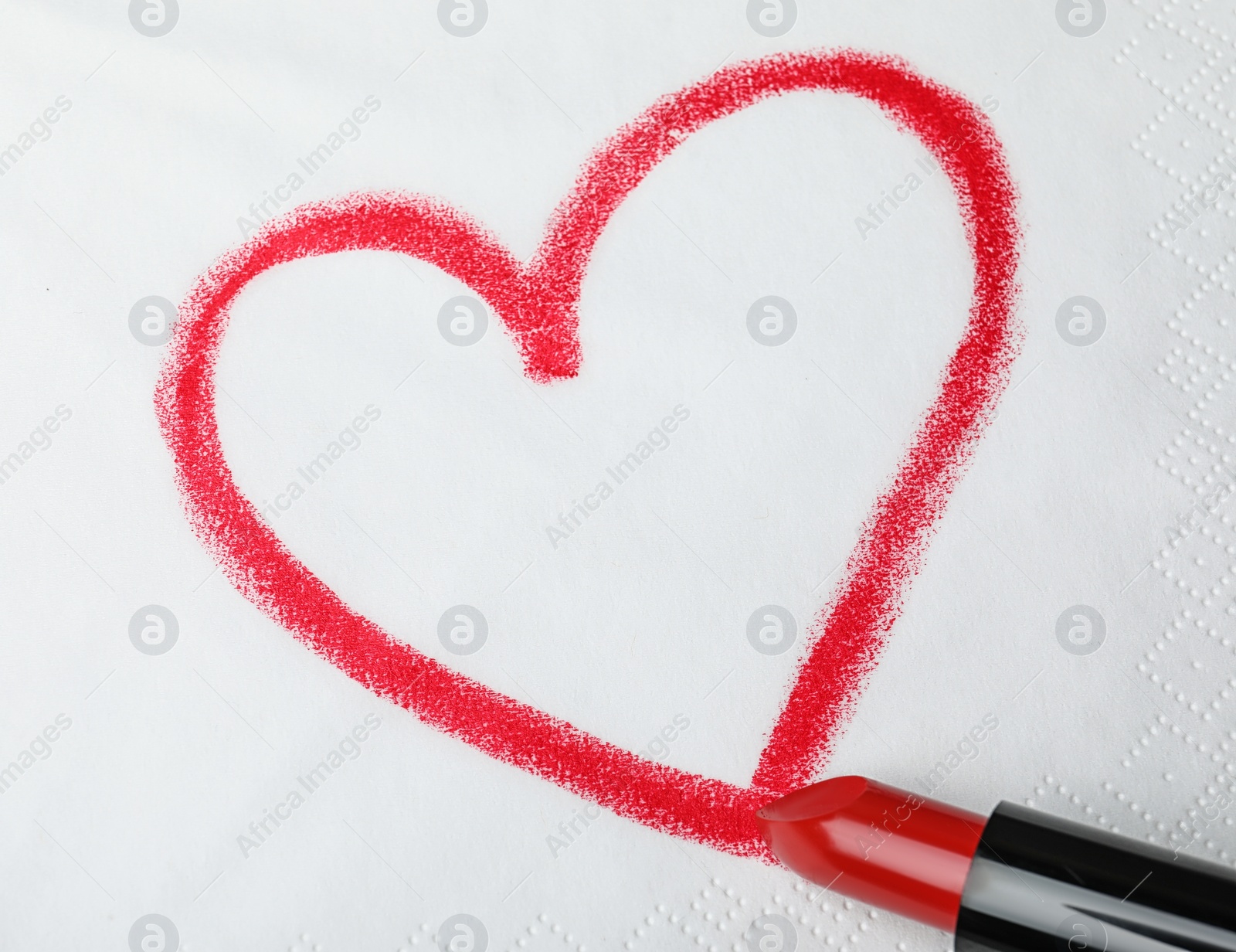 Photo of Drawing heart with lipstick on paper napkin, top view