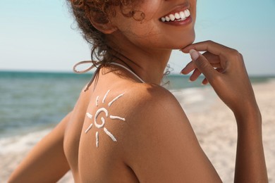 Photo of African American woman with sun protection cream on shoulder at beach, closeup