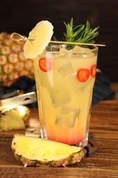 Photo of Spicy pineapple cocktail with chili pepper, rosemary and fresh fruit on wooden table