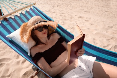 Young woman reading book in hammock on beach