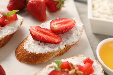 Delicious ricotta bruschettas with strawberry and mint on grey table