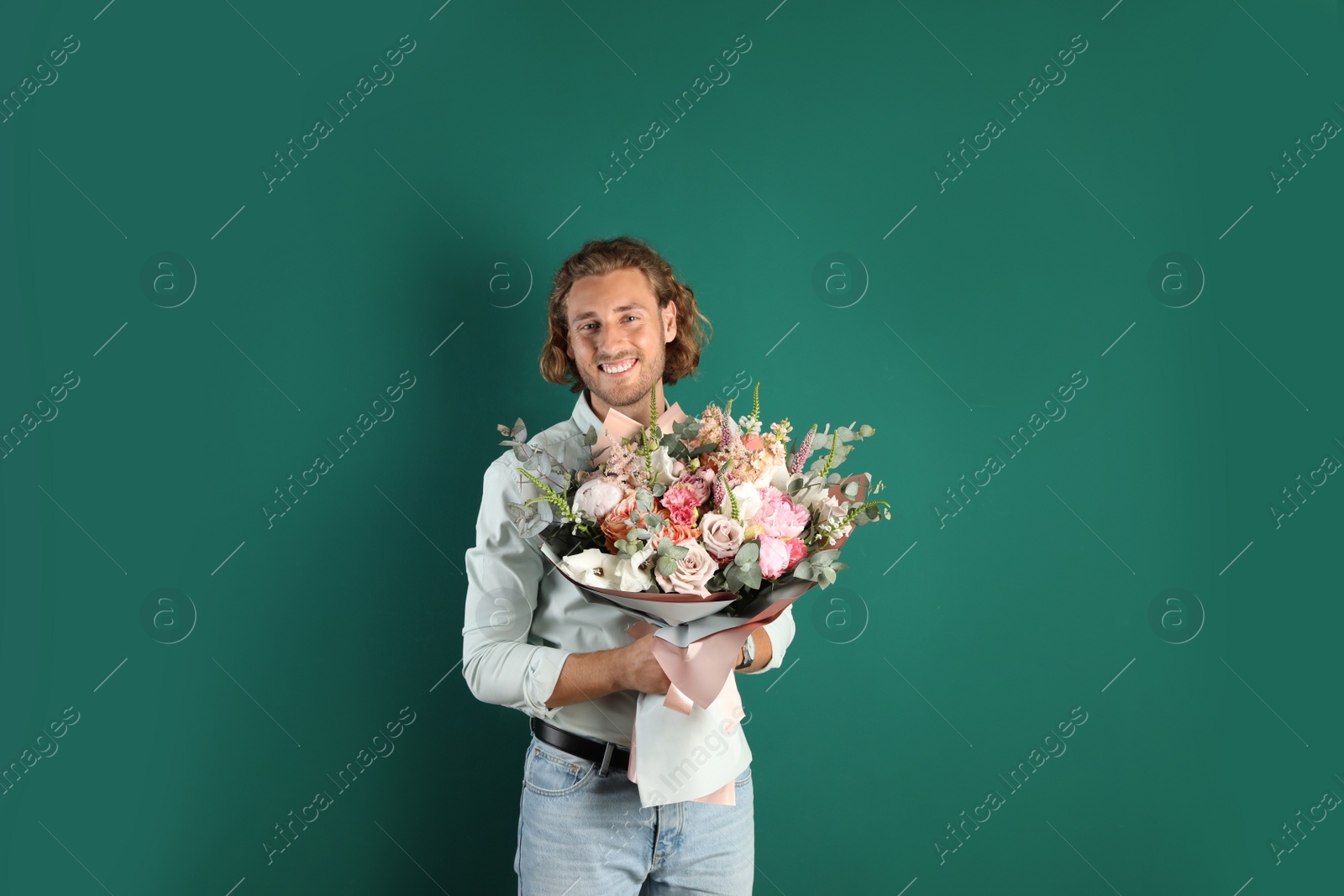 Photo of Young handsome man with beautiful flower bouquet on green background