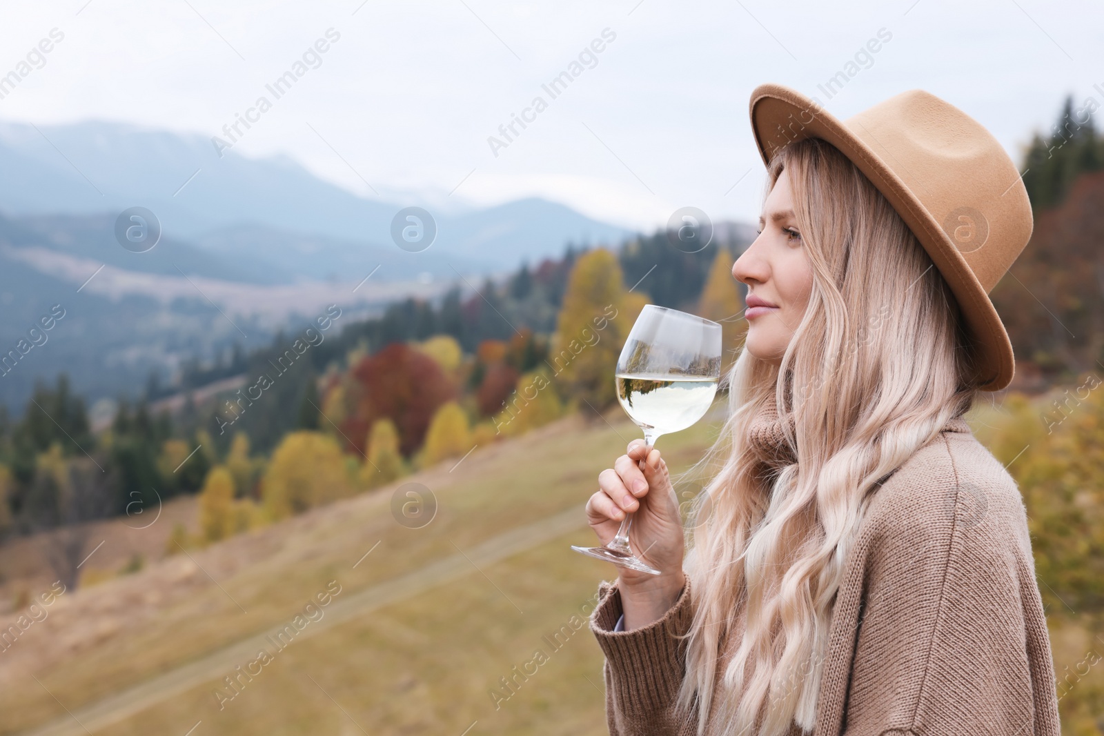 Photo of Young woman with glass of wine in peaceful mountains