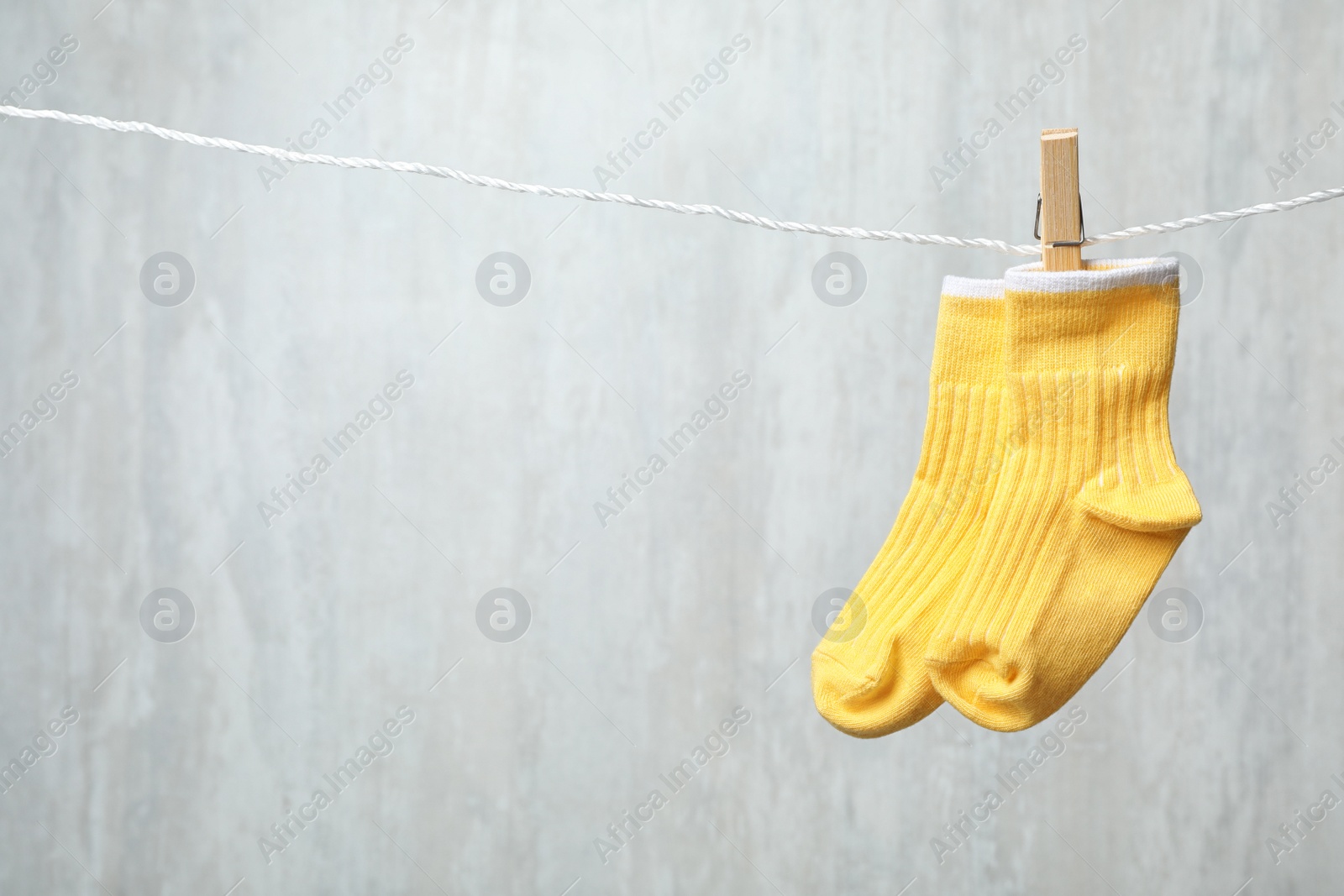 Photo of Pair of cute child socks on laundry line against light background. Space for text