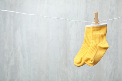 Pair of cute child socks on laundry line against light background. Space for text