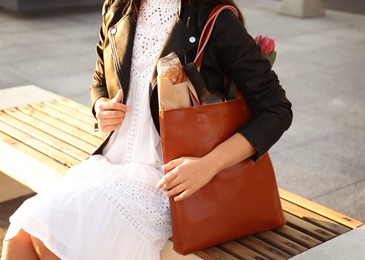 Photo of Woman with leather shopper bag sitting on bench, closeup
