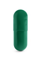 One green pill on white background. Medicinal treatment