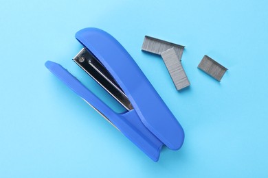 Photo of Stapler with staples on light blue background, flat lay