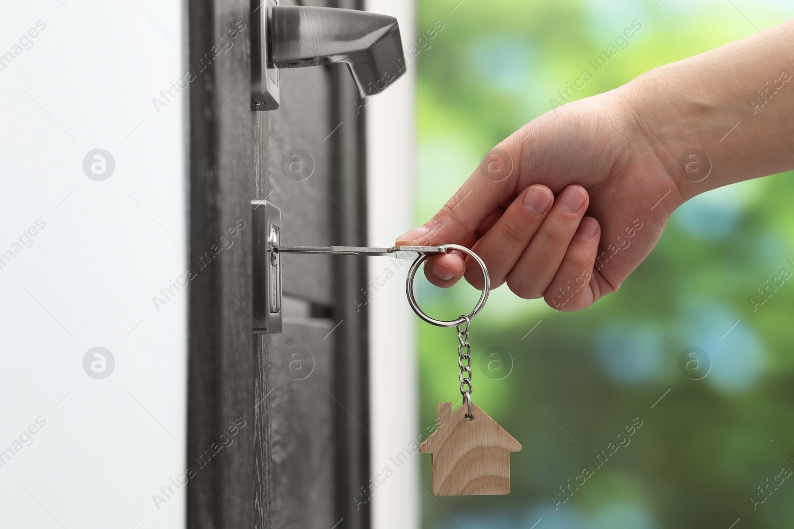 Photo of Woman unlocking door with key outdoors, closeup