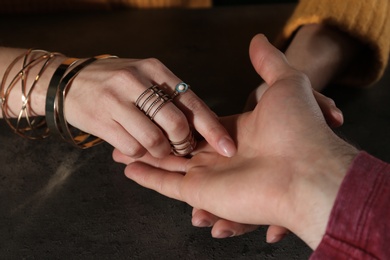 Photo of Chiromancer reading lines on man's palm at table, closeup