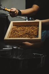 Photo of Man holding sieve with coffee beans indoors, closeup