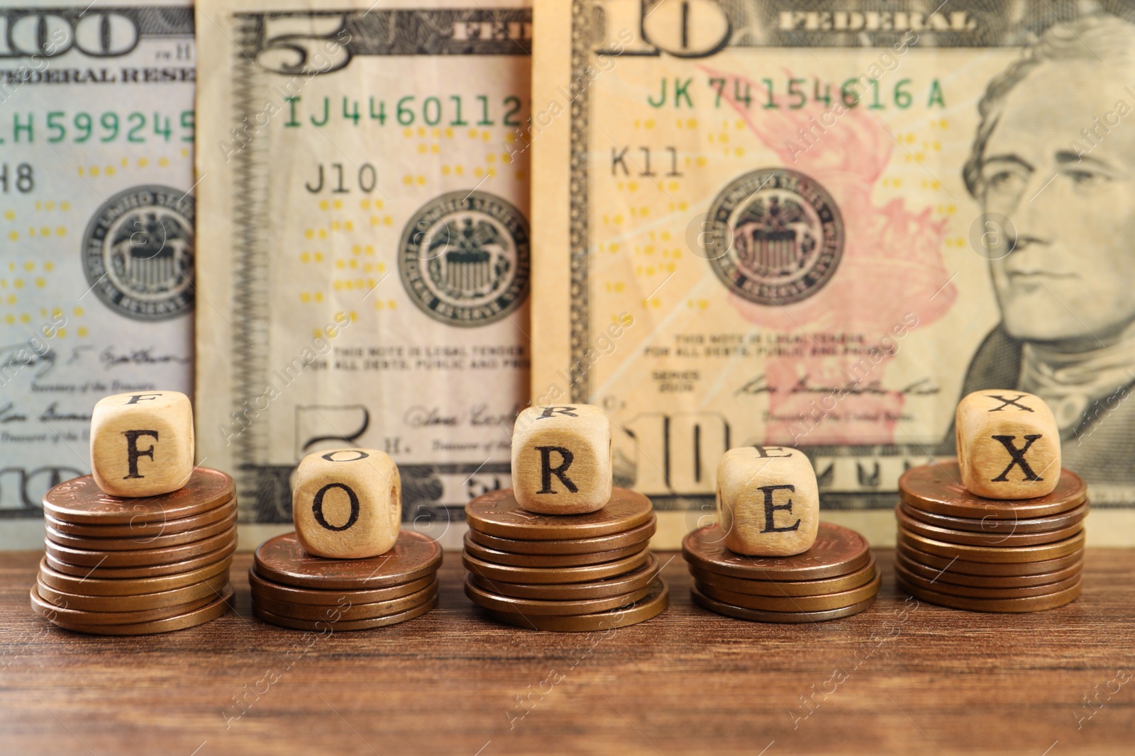 Photo of Word Forex made of wooden cubes with letters and stacked coins near banknotes on table