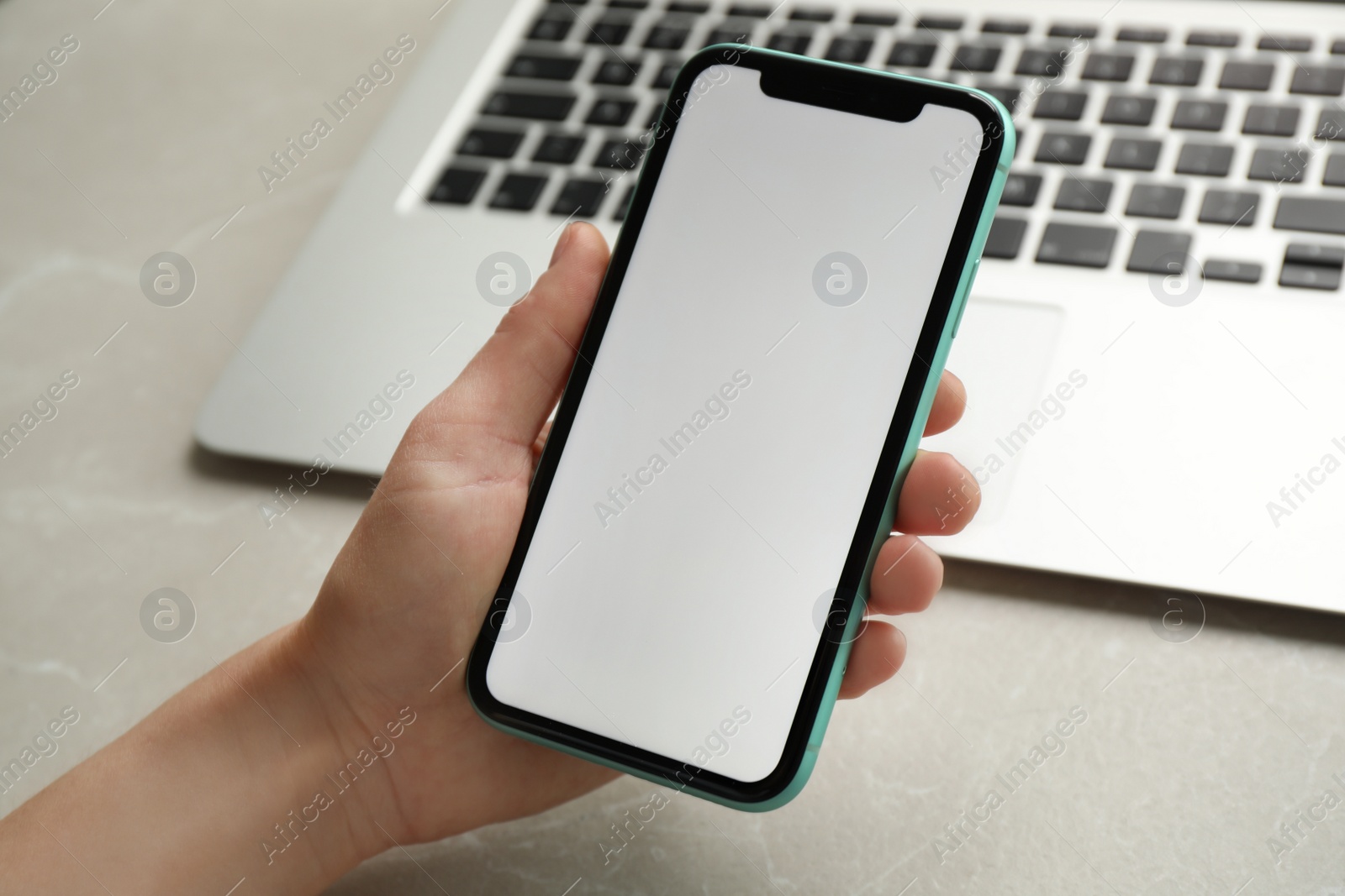 Photo of MYKOLAIV, UKRAINE - JULY 8, 2020: Woman holding Iphone 11 Pro Max with blank screen at workplace, closeup