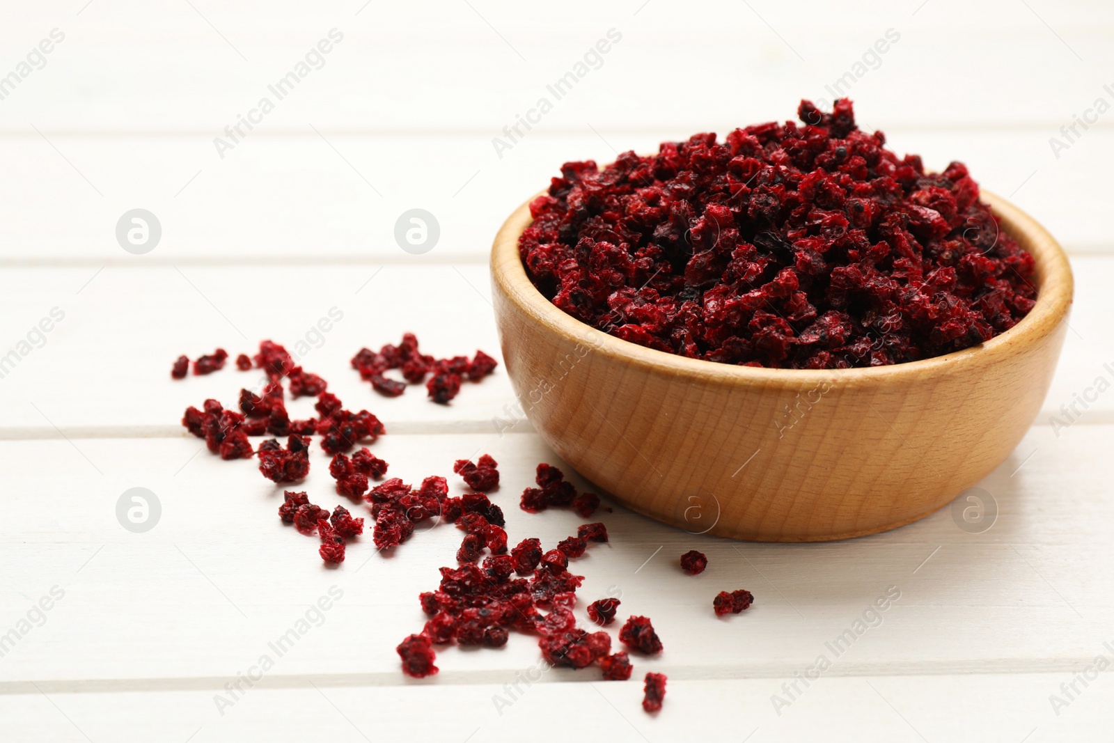Photo of Wooden bowl and dried red currant berries on white table