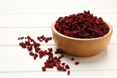 Wooden bowl and dried red currant berries on white table