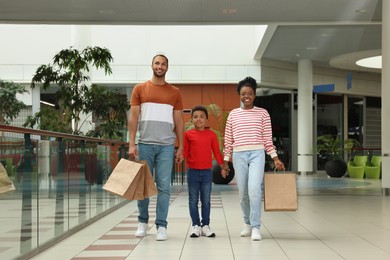 Photo of Family shopping. Happy parents and son with purchases in mall