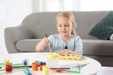 Photo of Cute little child painting at table indoors